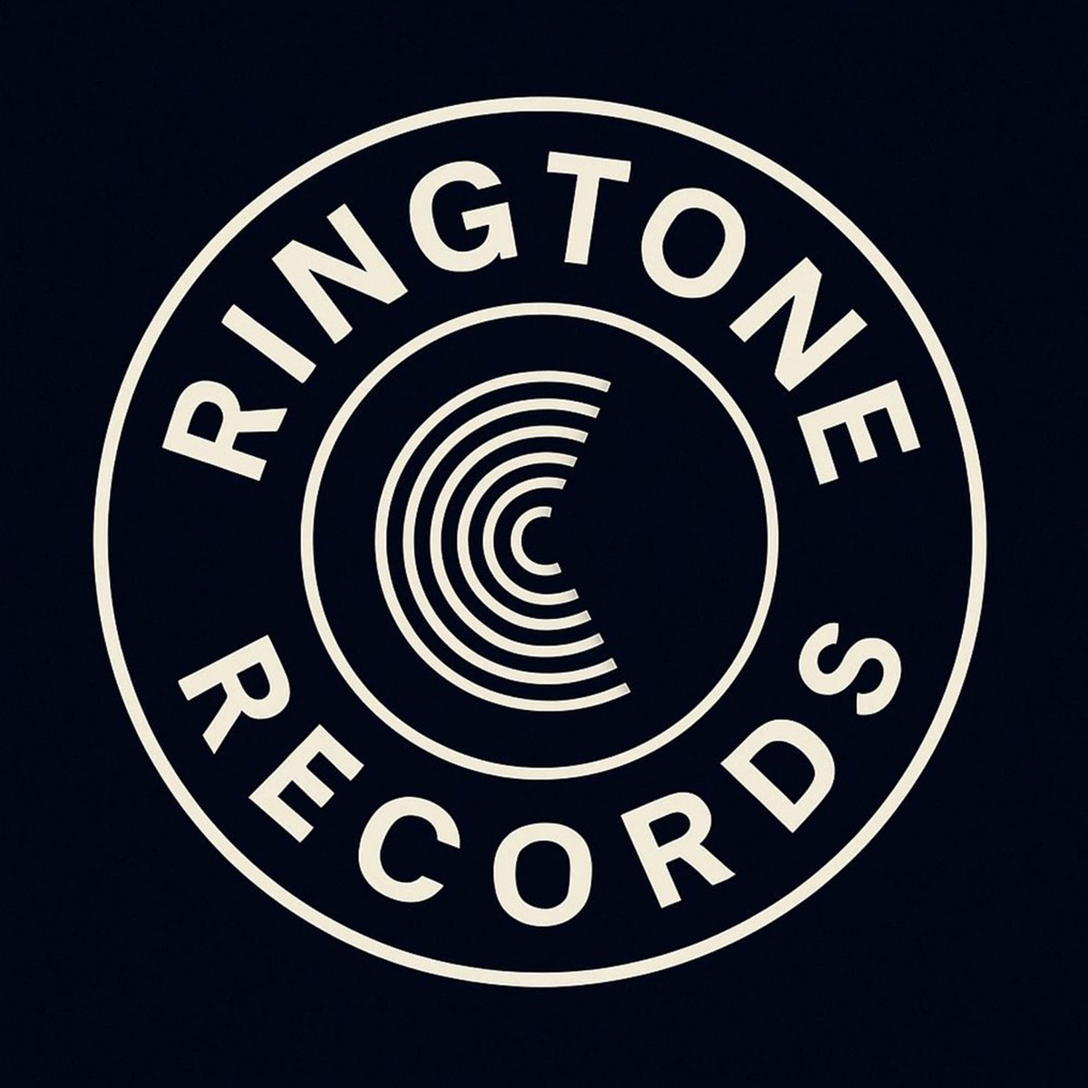Current circular Ringtone Records 26 label logo with cream lettering and concentric sound waves on a dark background.